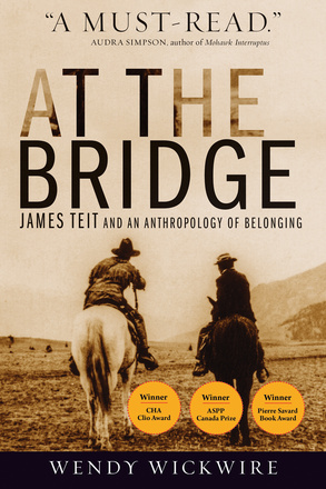 Cover: At the Bridge: James Teit and an Anthropology of Belonging, by Wendy Wickwire. photo: two men on horses in a large field, with a mountain in the background. One man rides a white horse and wears a wide-brimmed hat and a frilly leather outfit, while the other man rides a black horse and wears a small-brimmed hat and a black-and-white suit. At the top of the page is an endorsement, which reads, A must-read and is attributed to Audra Simpson, aithor of Mohawk Interruptus.